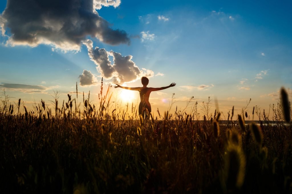 silhouette of sportive girl practicing yoga in field at sunrise min scaled
